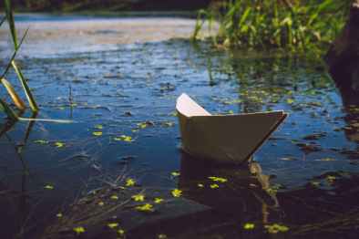 photo of white paper boat on body of water